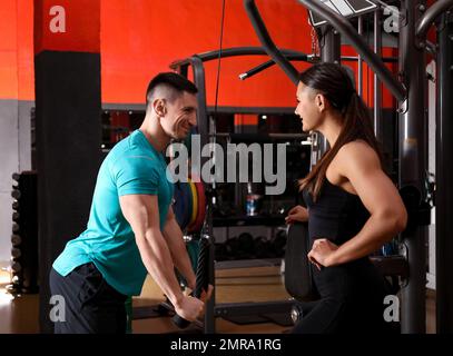 Trainer und Mann trainieren im Fitnessstudio Stockfoto