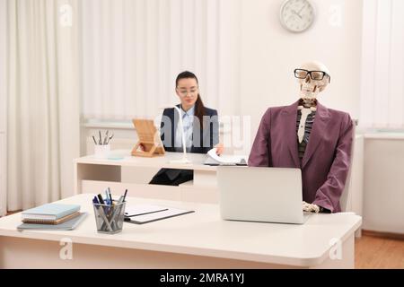 Junge Frau, die mit dem Skelett im Büro arbeitet Stockfoto