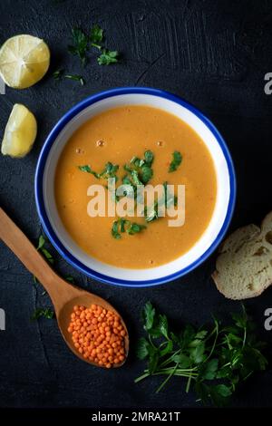 Rotes Linsensuppenpüree in einer Schüssel mit dunklem Hintergrund. Traditionelle Küche aus dem Nahen Osten. Veganes Essen. Stockfoto
