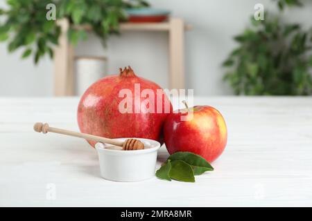 Honig, Apfel und Granatäpfel auf einem weißen Holztisch. Rosh Hashana Urlaub Stockfoto