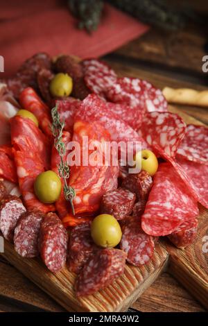 Leckere Salami mit anderen Delikatessen, serviert auf einem Holztisch Stockfoto