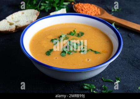 Rotes Linsensuppenpüree in einer Schüssel auf dunklem Hintergrund. Traditionelle Küche aus dem Nahen Osten. Veganes Essen. Stockfoto