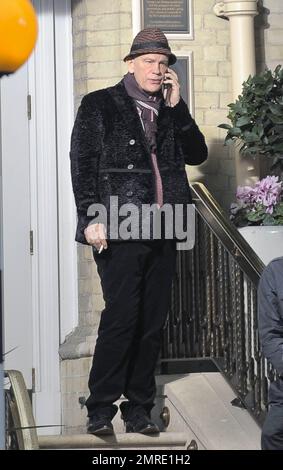 Schauspieler John Malkovich raucht eine Zigarette, während er am Drehort „Red 2" in London, Großbritannien, teilnimmt. 12. November 2012 Stockfoto