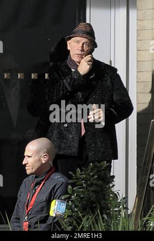 Schauspieler John Malkovich raucht eine Zigarette, während er am Drehort „Red 2" in London, Großbritannien, teilnimmt. 12. November 2012 Stockfoto