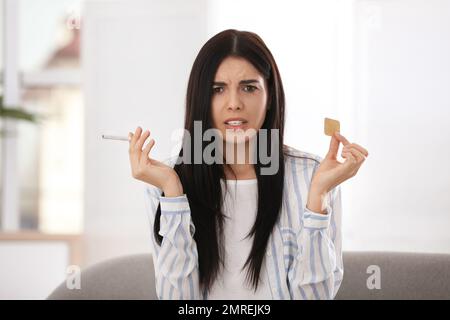 Emotionale junge Frau mit Nikotin-Pflaster und Zigarette zu Hause Stockfoto