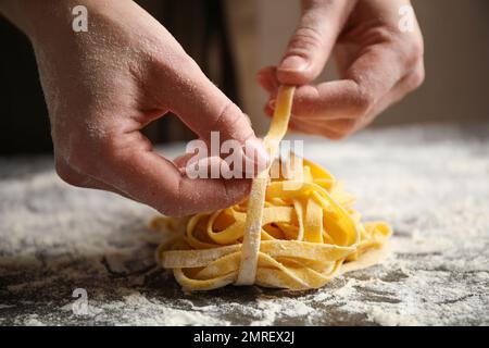 Eine Frau, die Pasta am Tisch hält, Nahaufnahme Stockfoto