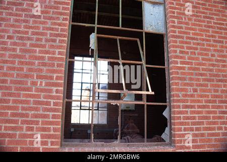 Zerbrochener Fensterrahmen in einem verlassenen roten Ziegelgebäude Stockfoto