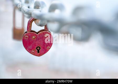 Rotes, herzförmiges Schloss hängt an der Brückenkette, Hochzeitsbrust ist Symbol für ewige Liebe, Kopierraum Stockfoto