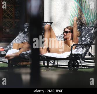 Kelly Bensimon ist am Pool in der historischen Versace Mansion in South Beach zu sehen, während sie mit ihrer Tochter Thaddeus Ann Urlaub macht. Die 46 Jahre alte Reality Star zeigt ihre Figur in einem braunen Bikini, während sie sich sonnt und etwas liest. Miami Beach, Florida 14. Juni 2014. Stockfoto