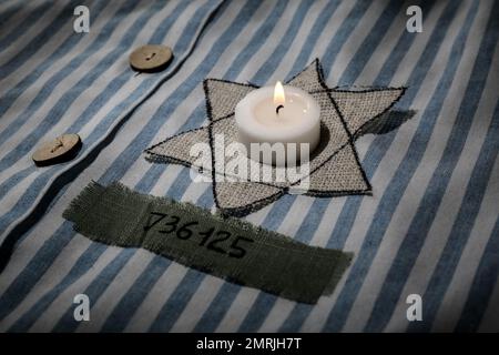 Brennende Kerze, jüdische Marke und Nummer auf der Uniform, Nahaufnahme. Internationaler Holocaust-Gedenktag Stockfoto