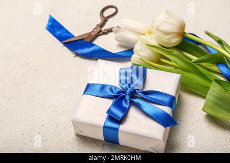 Geschenkbox, wunderschöne Tulpenblumen und Scheren auf hellem Hintergrund. Feier zum Frauentag Stockfoto