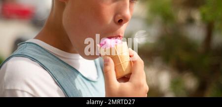Der Junge hält rosa Eis in der Hand. ISS Beereneis. Nahaufnahme der Hand. Stockfoto