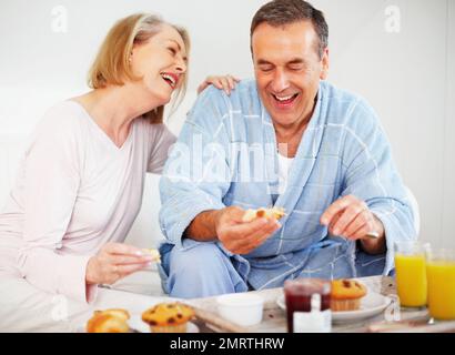 Ein Paar frühstückt mit einem erwachsenen Mann, der Butter aufträgt. Porträt eines romantischen Paares, das mit einem erwachsenen Mann frühstückt, der Butter aufträgt. Stockfoto