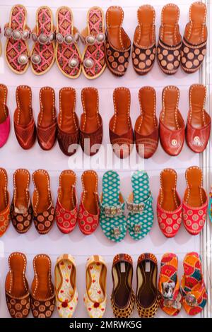 Bunte handgemachte Chappalls (Sandalen), die auf einem indischen Markt verkauft werden, handgefertigte Lederschuhe, traditionelle Schuhe. Stockfoto