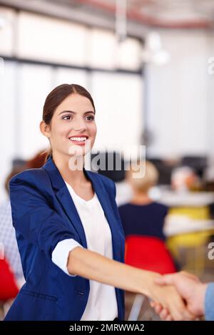 Das Treffen und die Begrüßung. Eine attraktive junge Geschäftsfrau, die einem Kollegen die Hand schüttelt. Stockfoto