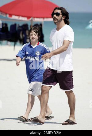 Der argentinische Schauspieler Fabian Mazzei umarmt seine Freundin, das argentinische Modell und die Schauspielerin Araceli Gonzalez, während sie eine schöne Zeit mit der Familie am Strand von Miami verbringen. Gonzalez, die für Fotografen lächelte, als sie in ihrem langen schwarzen Cover vom Strand wegging, schien sehr glücklich zu sein, als sie ihre Louis Vuitton Tragetasche und das Nylon Magazin trug. Miami, Florida 10/02/10. Stockfoto