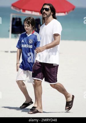 Der argentinische Schauspieler Fabian Mazzei umarmt seine Freundin, das argentinische Modell und die Schauspielerin Araceli Gonzalez, während sie eine schöne Zeit mit der Familie am Strand von Miami verbringen. Gonzalez, die für Fotografen lächelte, als sie in ihrem langen schwarzen Cover vom Strand wegging, schien sehr glücklich zu sein, als sie ihre Louis Vuitton Tragetasche und das Nylon Magazin trug. Miami, Florida 10/02/10. Stockfoto