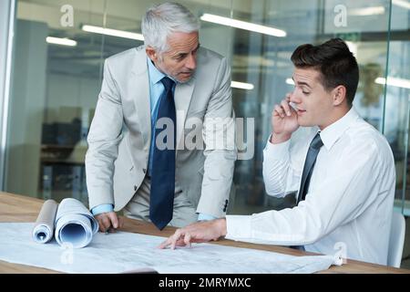 Zwei Architekten, die einen Bauplan überarbeiten. Stockfoto