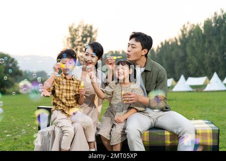 Die Familie bläst Blasen unter der untergehenden Sonne Stockfoto