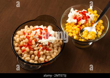 Esquites mit Mais und weißen Kidney Beans, Käse, Mayonnaise und Chili auf dunklem Hintergrund. Mexikanisches Street Food Stockfoto