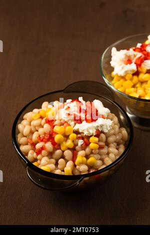 Esquites mit Mais und weißen Kidney Beans, Käse, Mayonnaise und Chili auf dunklem Hintergrund. Mexikanisches Street Food Stockfoto