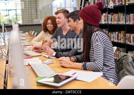 Hart an einem Gruppenprojekt zu arbeiten. Schüler, die an Computern in einer Universitätsbibliothek arbeiten. Stockfoto