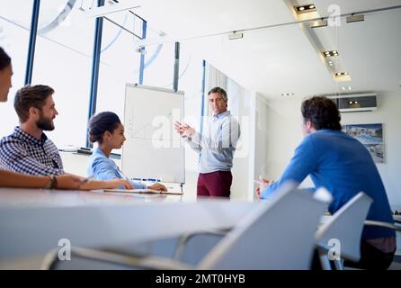Es geht um Strategie. Ein Geschäftsmann, der während einer Vorstandssitzung eine Präsentation mithilfe eines Whiteboards vorführt. Stockfoto