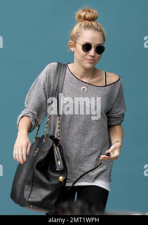 Miley Cyrus trägt ein graues Oberteil mit schwarzen Leggings und eine große schwarze Handtasche, wenn sie ihren Pilates-Kurs in Los Angeles, Kalifornien, verlässt. 12. Juli 2012 . Stockfoto