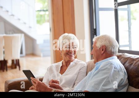 Wie cool ist dieser Honig. Ein älteres Paar, das zu Hause ein digitales Tablet verwendet. Stockfoto