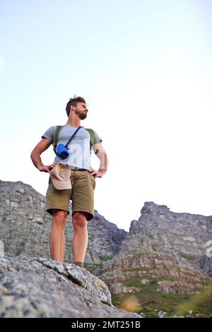 Die Aussicht von oben. Ein gutaussehender junger Mann, der beim Wandern die Aussicht genießt. Stockfoto