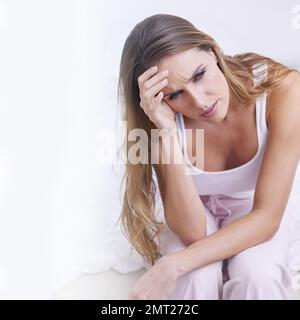 Was letzte Nacht passiert ist. Eine unglückliche junge Frau, die mit dem Kopf in der Hand sitzt. Stockfoto