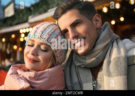 Glückliches Paar in warmen Kleidern auf der Wintermesse. Weihnachtszeit Stockfoto