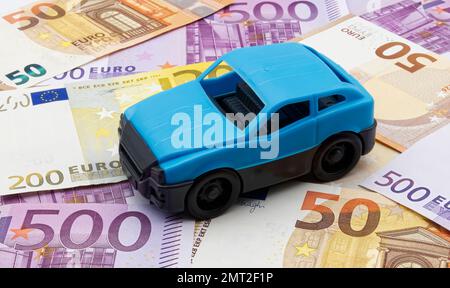 Blaues Modellauto isoliert mit Euro-Hintergrund. Reisekostenkonzept. Stockfoto