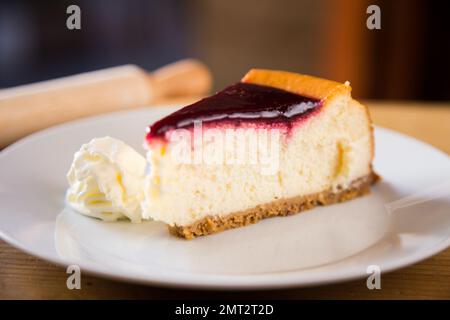 Käsekuchen mit Soße aus rotem Obst und frischem Obst wie Himbeeren, Heidelbeeren oder Erdbeeren. Stockfoto