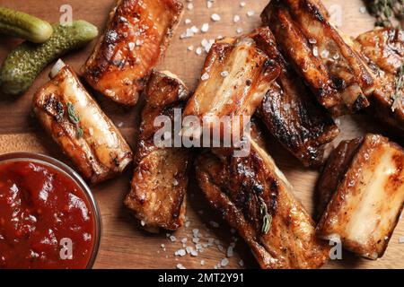 Köstliche gegrillte Rippchen mit Sauce auf Holztisch, flach liegend Stockfoto
