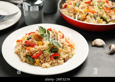 Köstlicher Reispilaf mit Huhn und Gemüse auf einem schwarzen Tisch Stockfoto