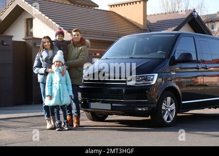 Glückliche Familie mit kleinen Kindern in der Nähe eines modernen Autos auf der Straße Stockfoto