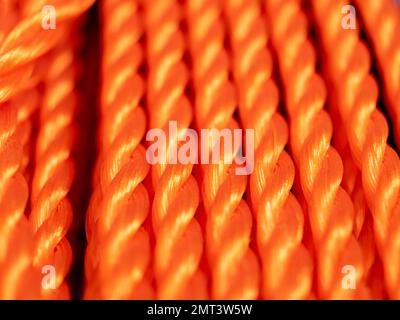 Nahaufnahme eines orangefarbenen Seils. Textur geflochtener Seile. Orangefarbener Hintergrund. Stockfoto