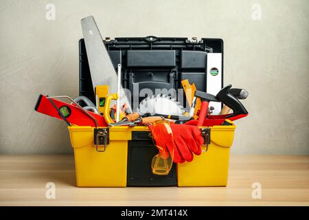 Box mit verschiedenen Zimmermannswerkzeugen auf Holztisch Stockfoto