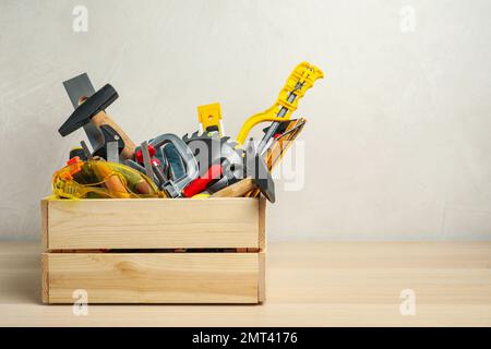 Kiste mit verschiedenen Zimmermannswerkzeugen auf Holztisch. Platz für Text Stockfoto