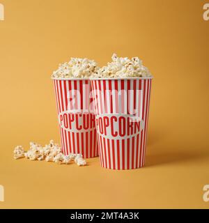 Köstliches Popcorn in Pappbechern auf gelbem Hintergrund Stockfoto