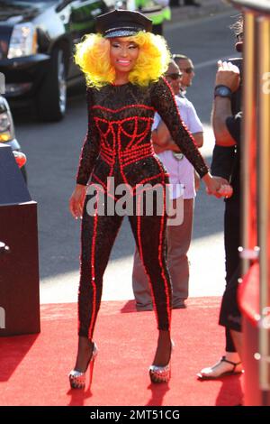Der Sänger Nicki Minaj trägt einen schwarz gemusterten Unitard mit schwarzer Mütze, hohen Absätzen mit schwarzen Spikes und einer leuchtend gelben Perücke und wird bei den MTV Video Music Awards 2012 im Staples Center in Los Angeles, Kalifornien, ausgezeichnet. 6. September 2012 Stockfoto