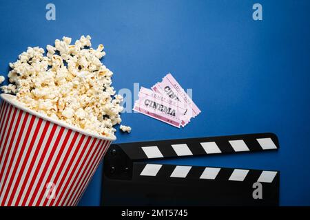 Flach liegend mit köstlichem Popcorn und Kinoartikeln auf blauem Hintergrund Stockfoto