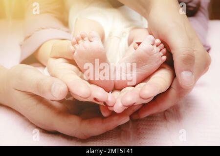Babyfüße in den Händen von Mutter und Vater. Meine Eltern und ihr Kind. Happy Family Concept. Wunderschönes konzeptionelles Bild der Elternschaft Stockfoto