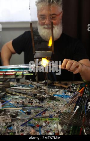 Venedig, Italien - 5. September 2022: Glasarbeiter, die das Glas mit einer sehr heißen Flamme in ihrer Kunsthandwerkstatt in Venedig Formen. Italien Stockfoto