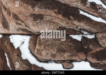 Steinklippe mit Schnee darauf. Stockfoto