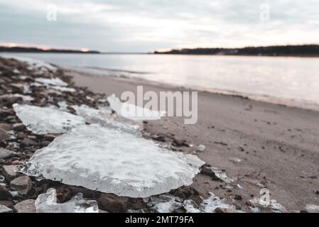 Kleine Gletscher des ersten Eisens liegen im Herbst bei Sonnenaufgang am Sandstrand in der Nähe des Flusses Vilyui in Yakutia Stockfoto