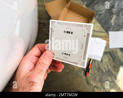 London, Vereinigtes Königreich - 1. Januar 2022: Nahaufnahme des männlichen Handhalters mit neuem Vaillant VR51-Raumthermostat, Rückwandmontageplatte - Internet IOT-Gerät mit Verbindung Stockfoto