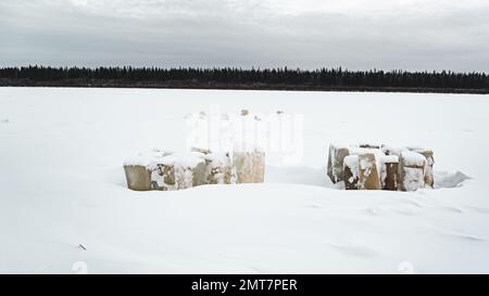 Die Säulen aus geschnitztem Eis sind im Winter auf dem Vilyui River in Yakutia vor dem Hintergrund eines Taigawaldes mit Schnee bedeckt. Stockfoto