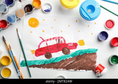 Flachliegenkomposition mit Kindermalerei von Auto auf weißem Tisch Stockfoto